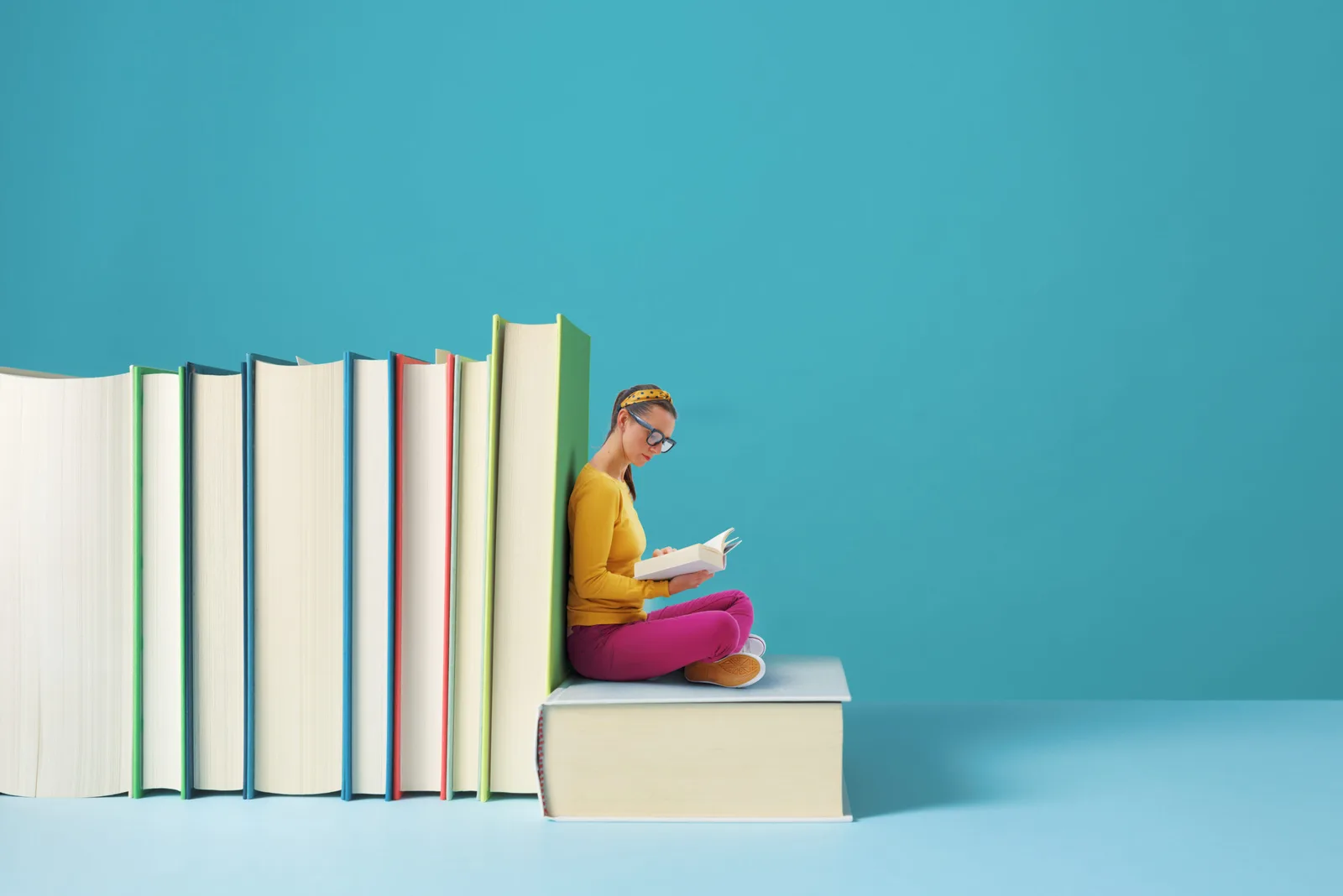 A reader seated beside an oversized book
